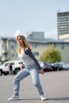 Young woman performs dance moves in urban setting on sunny day photo