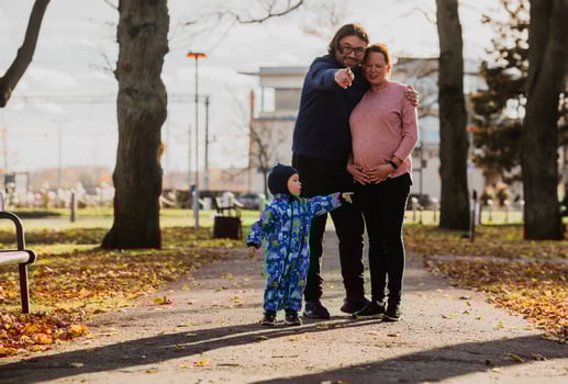 A loving couple strolls through a sunlit park with their young son, surrounded by the vibrant colors of autumn, enjoying a joyful and peaceful family moment together. photo