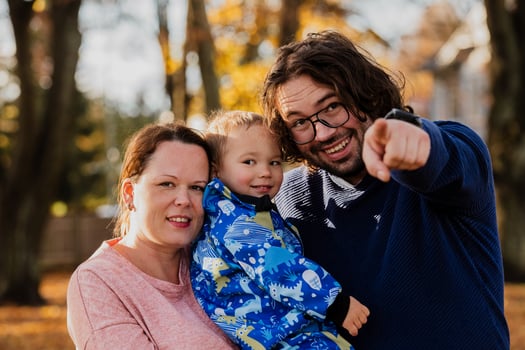 On a sunny autumn day in the park, a mother and father lovingly embrace their young son, sharing moments of laughter and joy as they play together photo