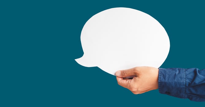 Close-up of hand holding a white speech bubble against a blue background photo