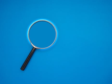Search concept. A magnifying glass on a blue background with copy space for text photo
