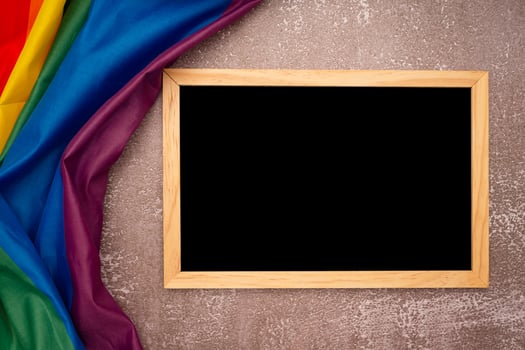 Top view of the rainbow flag or LGBT and a blank mini chalkboard with the wooden border over a cement floor photo