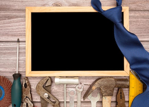 Happy Father's Day. A blank mini chalkboard, necktie, and construction tools on a wooden table photo