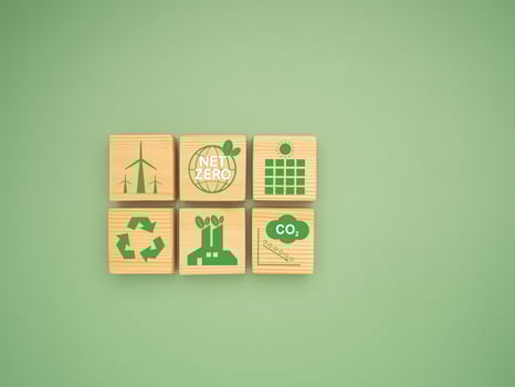 Net-zero greenhouse gas emissions target. Wooden cubes with green icons over a green background photo