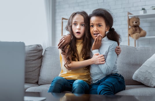 Two scared girls watching horror film on laptop at home photo