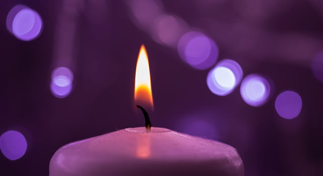 Close up of one burning candle with blurred Christmas light background photo