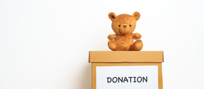 Kid Donation, Charity, Volunteer, Giving and Delivery Concept. Bear doll and Clothes with Donation box at home for support and help poor, refugee and homeless people. Copy space for text photo