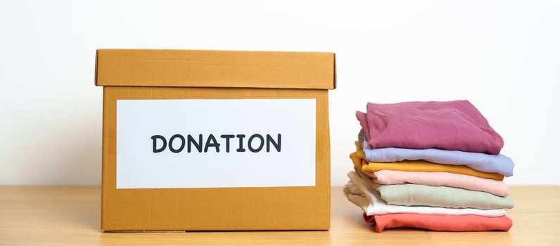 Donation, Charity, Volunteer, Giving and Delivery Concept. Clothes with Donation box at home or office for support and help poor, refugee and homeless people. Copy space for text photo