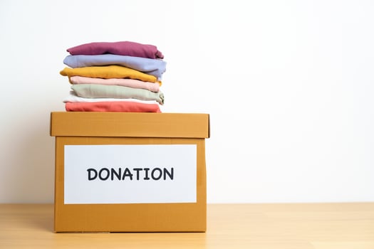 Donation, Charity, Volunteer, Giving and Delivery Concept. Clothes with Donation box at home or office for support and help poor, refugee and homeless people. Copy space for text photo