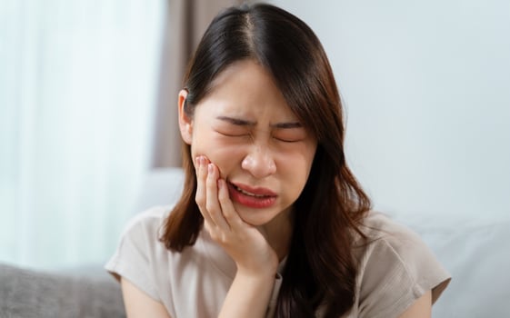 A woman is in pain and is holding her face having a toothache. Healthcare and medical concept. photo