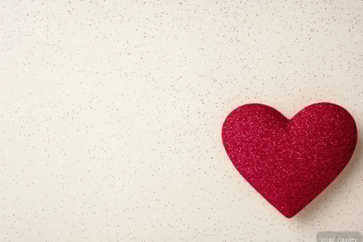 Heart shape painted on textured surface with splashes of red and white in background photo