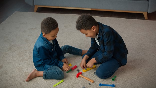 Ethnic African American multiracial multiethnic boys kids schoolboys pupils sons indoors at home children brothers cousins friends on floor carpet play with toys tools playing repair game together photo