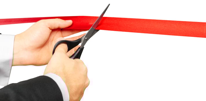 Scissors are cutting red ribbon or tape. Isolated on white background. photo