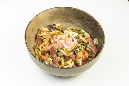 Beef Yakisoba Noodles topped with green onions served in bowl isolated white background side view of Japanese food photo
