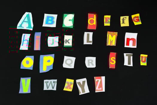 Colorful newspaper alphabet isolated on black photo