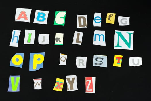 Colorful newspaper alphabet isolated on black photo