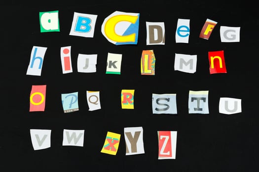 Colorful newspaper alphabet isolated on black photo