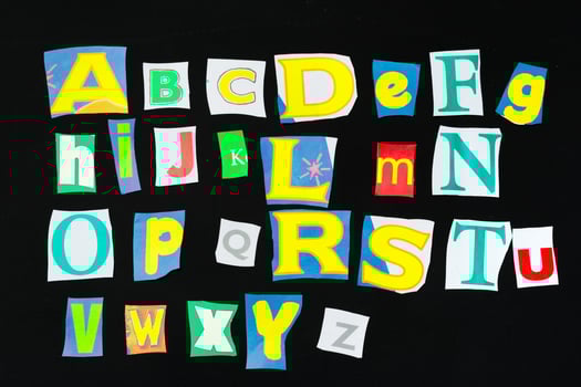 Colorful newspaper alphabet isolated on black photo