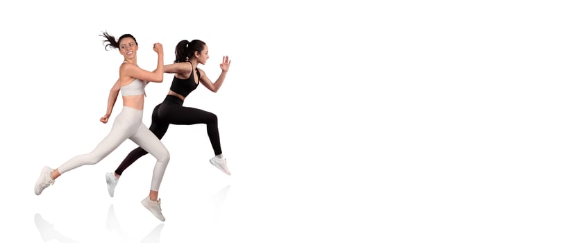 Two women in sporty outfits are sprinting energetically against a plain backdrop. Their dynamic movements showcase fitness and determination, highlighting athleticism and teamwork. photo