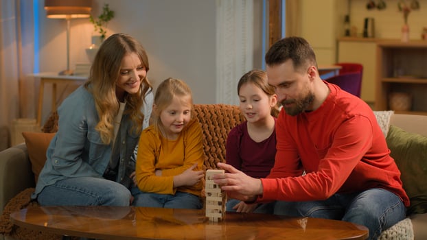 Happy family Caucasian parents mom dad play with kids build wooden blocks little preschool children girls siblings daughters enjoy playtime playing game at home elementary education learning childhood photo