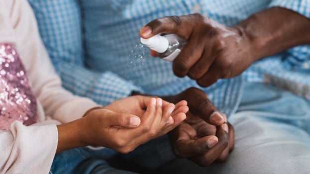 Hygiene during epidemic. Unrecognizable African American grandparent and his grandchild cleaning hands with sanitizer, closeup. Panorama photo