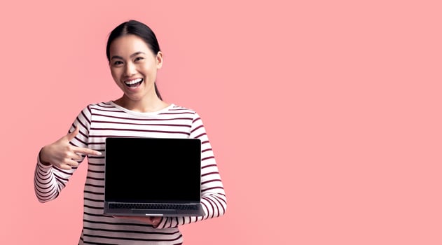 Happy Young Asian Woman Pointing At Laptop With Blank Black Screen In Her Hands, Excited Korean Lady Indicating Free Copy Space For Website Design, Standing Isolated On Pink Background, Mockup Image photo