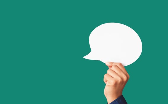 Close-up of hand holding a white speech bubble on a green background photo