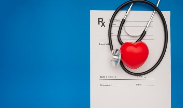 Top view of a stethoscope and a red heart shape over the medical prescription sheet on a blue background photo