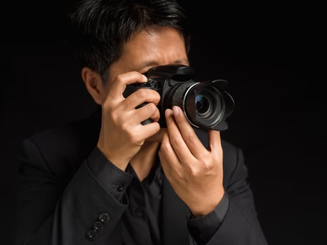 Photographer is shooting pictures with a digital camera while standing on a black background photo