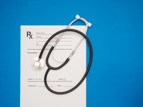 Top view of a stethoscope over the medical prescription sheet on a blue background photo