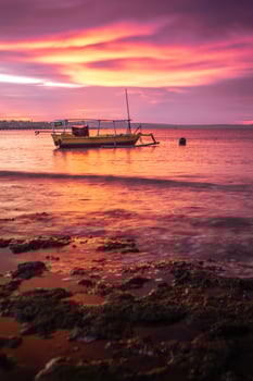 A fisherman's boat rests on the shore at Pasir Panjang Beach during sunset. photo