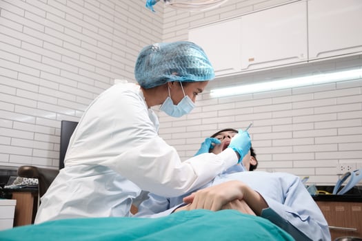 Asian female dentist examine young male patient teeth and toothache stomatology in dental clinic, well-being hygiene checks, and professional orthodontic healthcare work in doctor's office hospital. photo