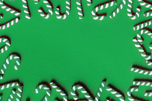 Flat lay Christmas composition with frame of candy canes on a green background. photo