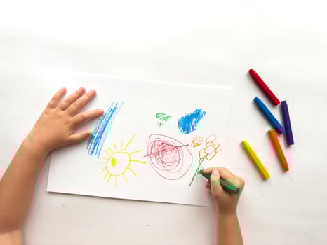 Childs colorful crayon drawing with bright sun, flowers, and geometric shapes on white paper photo