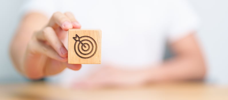 hand hold dartboard block with business goal, strategy, target, mission, action, objective, aim and success concept photo
