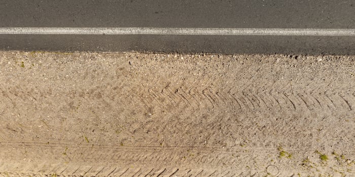 view from above on texture of asphalt road with median from gravel road with lawn photo