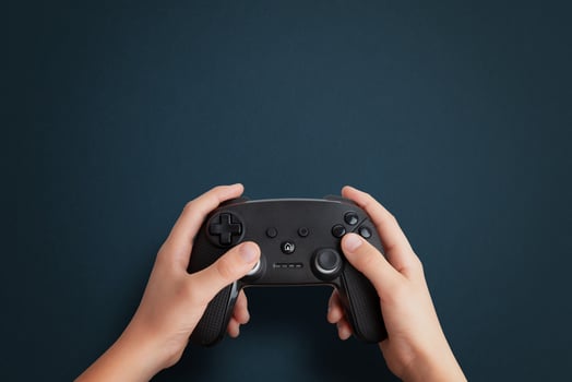 Top view of a hand holding a gamepad on a blue desk, flat lay composition with clean space for promotional text, ideal for gaming and tech branding photo