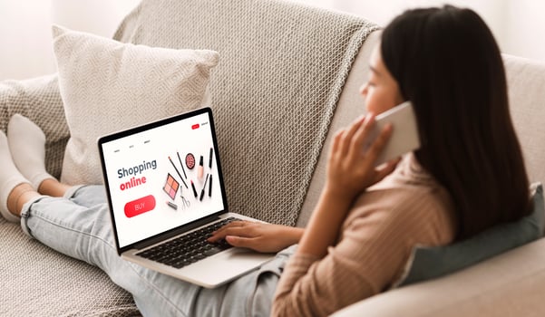Female Shopping Concept. Back view of woman browsing online make up store, talking on phone, sitting at home photo