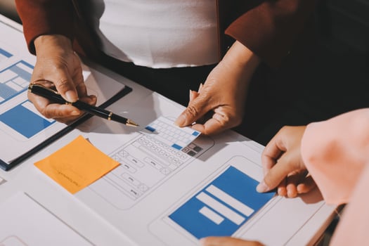 Two people are working on a project with a paper and pen photo
