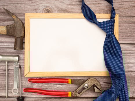 Happy Father's Day. A blank mini whiteboard, necktie, construction tools, a hammer, screwdriver, screws, and pliers are on a wooden table photo