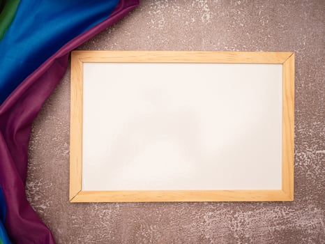 Top view of the rainbow flag or LGBT and a blank mini whiteboard with the wooden border over a cement floor photo