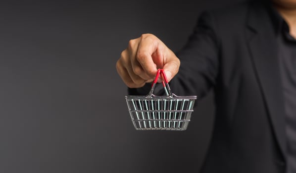Close-up of hand holding an empty mini shopping cart over a gray background. photo