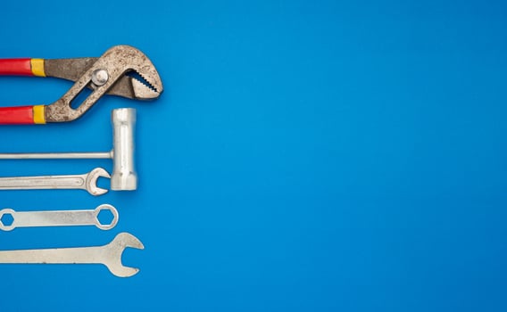 Work tools over a blue background. Pliers, screwdriver, and spanner photo