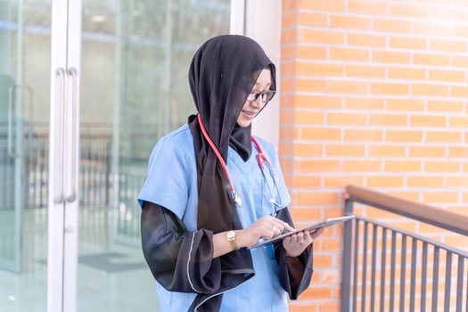 Female Muslim doctor in Abaya niqab traditional clothes works and check list on tablet at modern clinic office with sun fare background. photo