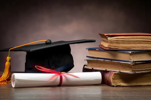 Graduation symbols of cap, diploma, and old books on a muted gradient backdrop photo