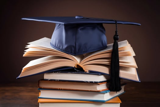 Graduation cap rests atop a stack of books, highlighting academic achievement photo