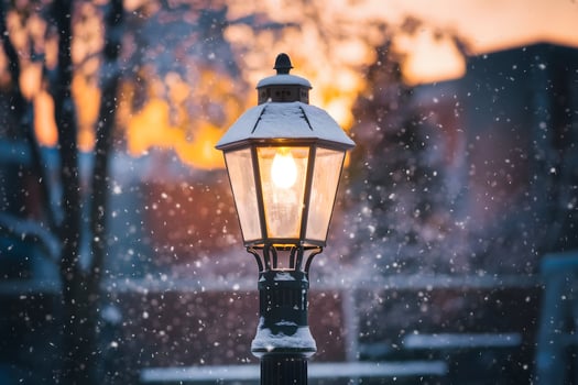 Vintage lamppost illuminated by golden light, surrounded by falling snowflakes photo