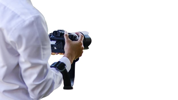 A detailed close-up of hands gently cradling a sleek black camera, symbolizing creativity and the art of capturing moments, set against a minimalist white background photo