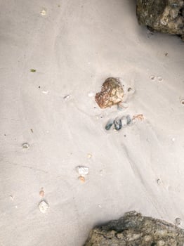 Rocks on the beach, surrounded by fine white sand carried by the waves photo