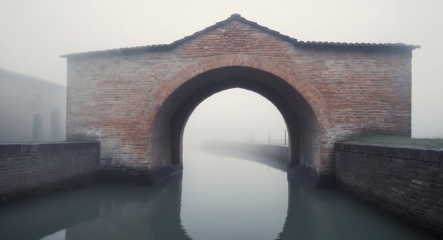A Tranquil Canal Scene Under a Brick Archway with Mist. photo